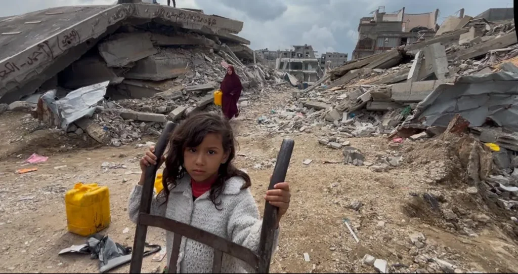 Meisje met kruiwagen tussen puin in oorlogsgebied – hulpbehoevende kinderen in noodsituaties