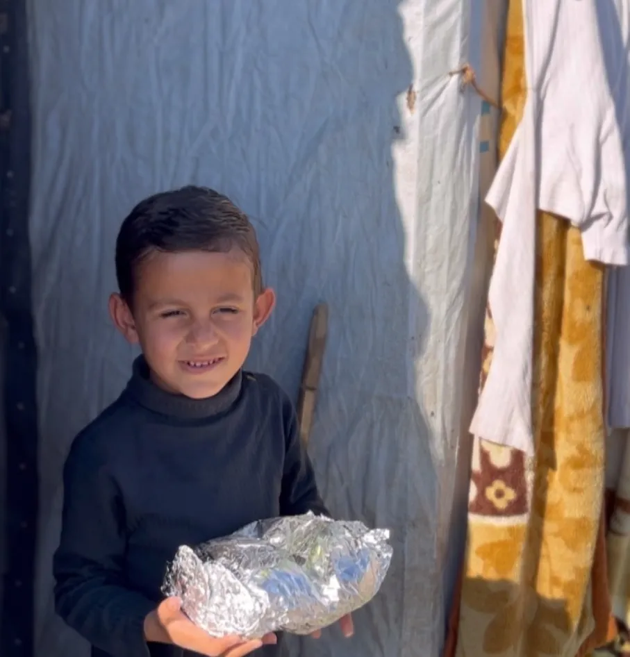 Kind in vluchtelingenkamp ontvangt maaltijd in aluminiumfolie